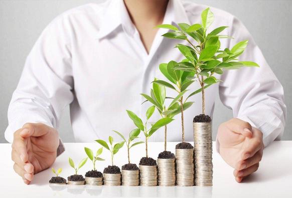 A businessman raises a stack of coins with a green plant emerging from them, representing investment and environmental awareness