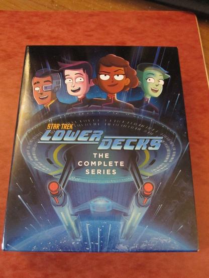 The complete series of Star Trek: Lower Decks on Blu-Ray. Characters (left to right) ... Sam Rutherford, Brad Boimler, Beckett Mariner and D'Vana Tendi. All above the U.S.S. Cerritos.