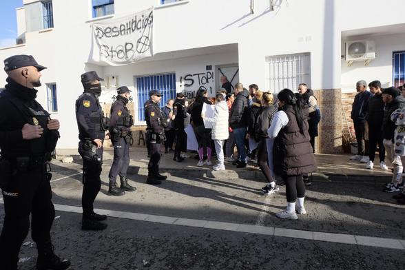 Almeria, Spanien, spanische Polizei bei einer Räumung von Landarbeiter:innen aus ihren Häusern, im Hintergrund Protestbanner der geräumten, im Vordergrund Landarbeiter:innen die protestieren.