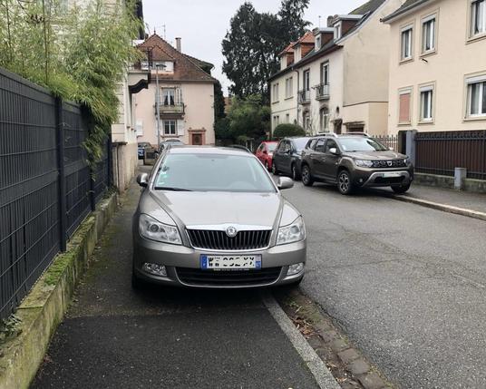 Une berline Skoda sur le trottoir rue de Wangenbourg, bloquant tout passage pour les piétons. De l’autre côté de la route, on peut apercevoir plusieurs autres voitures qui mordent sur le trottoir.