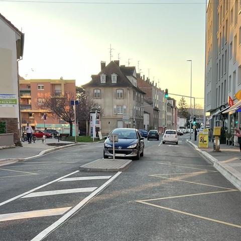 Une Peugeot 206 avec son conducteur a l’arrêt entre les deux voies de circulation, juste devant un séparateur sur la chaussée (pour un arrêt de bus). Son conducteur est dans le véhicule.