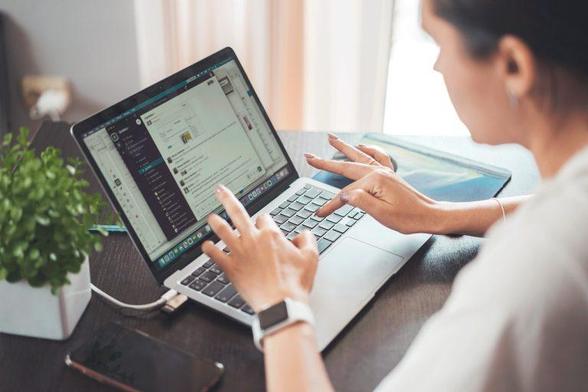 A woman engaged in typing on her laptop, showcasing concentration and productivity in a modern workspace