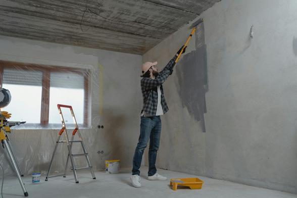  A man using a paint roller to paint a room, focused on applying a fresh coat of color to the wall