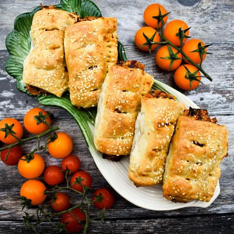 Sausage rolls on a platter with cherry tomatoes