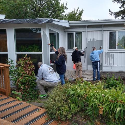 Four people paint a house. 
