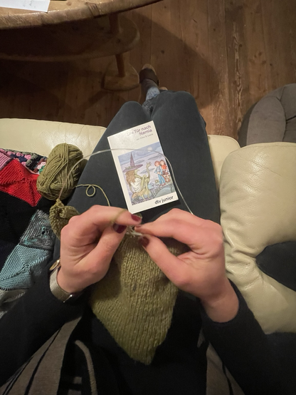 Strickende Hände und Buch „die Tür nach Narnia“