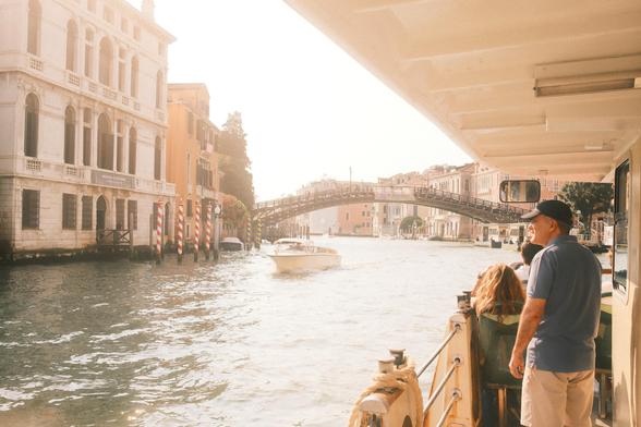 People on public transport boat in Venice view the canal and bridge