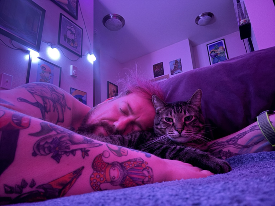 tattooed man cuddles with cat