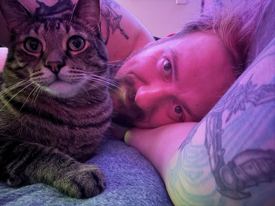 tattooed man cuddles with cat close up