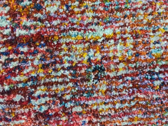 Colorful, textured rug with multicolored, short, fuzzy fibers.