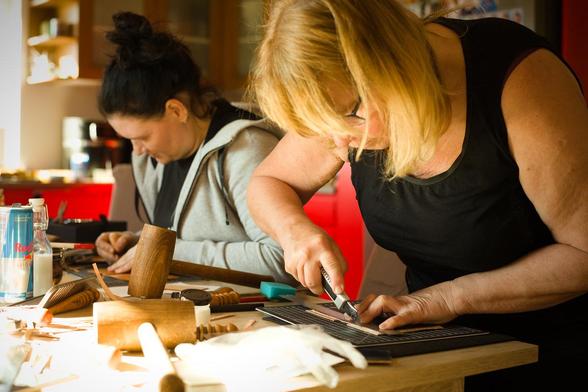 Another pair of my students at the workbench - cutting leather card wallet's edges straight.
