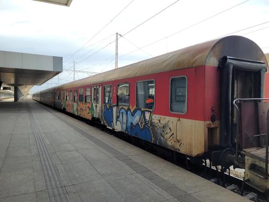 Carriage with doors in the middle. Red and white paint, covered in graffiti.