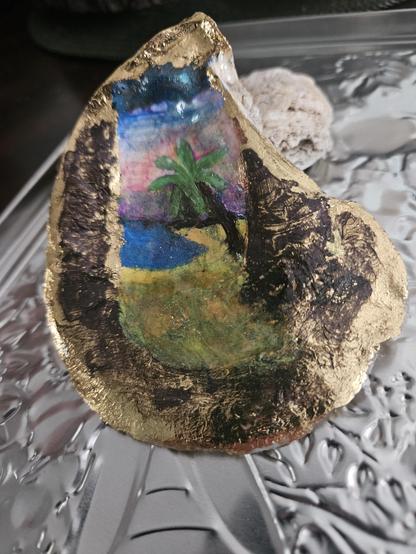 Finished painting of an island scene on an oyster shell.