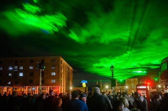A green light installation over the Royal Albert Dock in Liverpool at night.