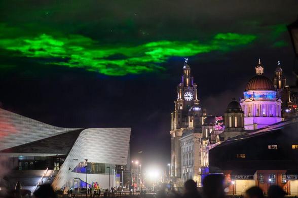 A green light installation over the waterfront in Liverpool at night.