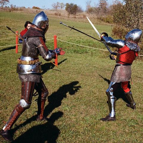 Two knights fighting in a ring. One has thrown his sword at the other, who parries while the sword is in midair. A marshal stands behind one of the knights.