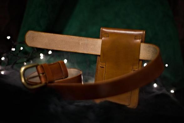This is a photo of medium brown leather belt bag suitable for a smaller item like a phone. Leather belt bag on the back side. Photo depicts how it would look if the bag was worn vertically on the belt. 