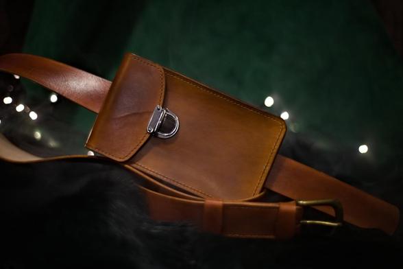 This is a photo of medium brown leather belt bag suitable for a smaller item like a phone. Leather belt bag on the front side. Photo depicts how it would look if the bag was worn horizontally on the belt. 