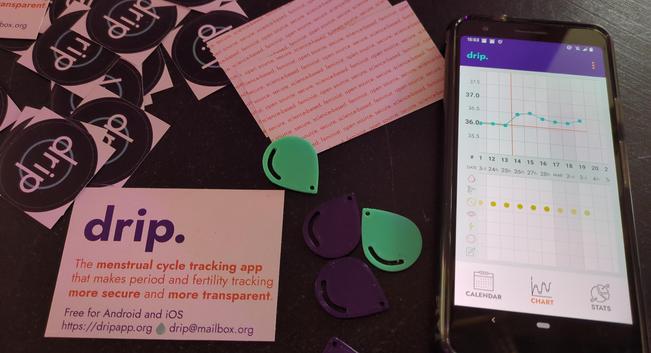 Dark purple and turquoise 3d printed drip icons (a drop) next to a phone showing the drip chart and some 'business' cards.