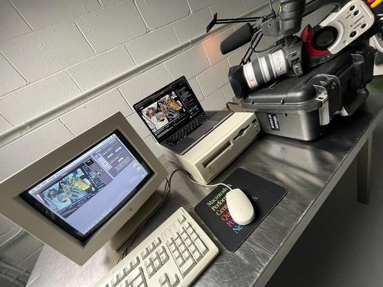 Photo of a DV camera pointed at a modern laptop, while hooked up to a Mac LC630 running video capture software