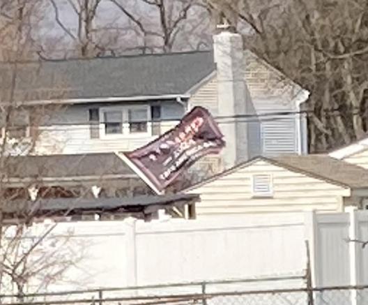 A Trump flag waving from a house, proudly proclaiming the inhabitants' love of fascism, corruption and being assholes.