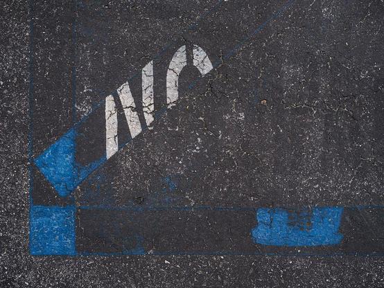 Old markings of handicap parking space with about half of "No" remaining.