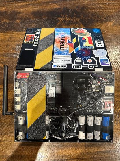 A picture of the bottom of a customized MNT Reform with stickers and hazard tape.