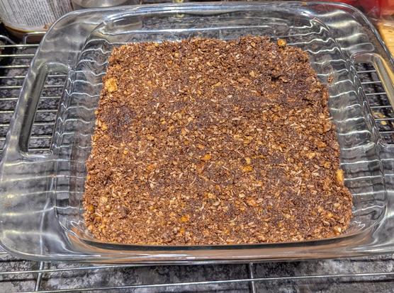 Base layer of coconut, gram cracker, egg, walnut, and cocoa powder in a glass tray