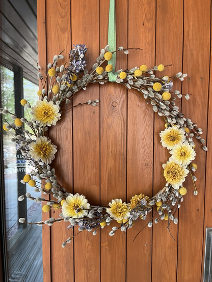 A wreath made of willow branches with catkins, yellow dahlia flowers and small round yellow flowers