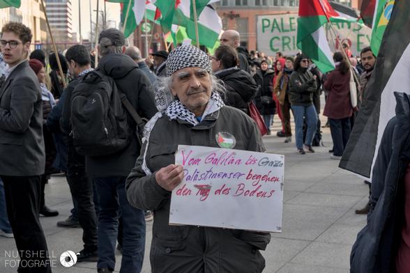 Ein Mann mit einem Schild mit der Aufschrift "Von Galiläa bis Gaza Palästinenser begehen den Tag des Bodens"