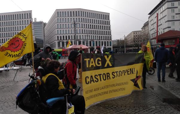 Kundgebung vor dem Bremer Hbf. Transparent Tag X Castor stoppen, Personen die es halten und Anti-Atom Fahnen.
