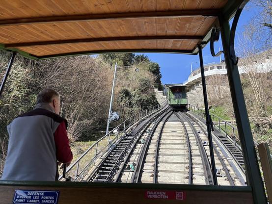 Foto aus einer Standseilbahn mit Blick zur höher gelegenen Station. Die andere Bahn kommt entgegen.