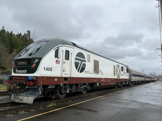Amtrak cascades train at depot in Eugene, Oregon under rainy cloudy skies. 