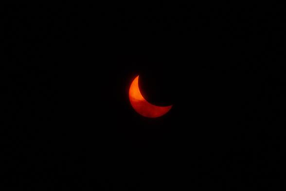 Partial solar eclipse. Some clouds are also in front of the sun. A small sunspot can be seen.
