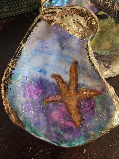 Oyster shell with a starfish painted on it.