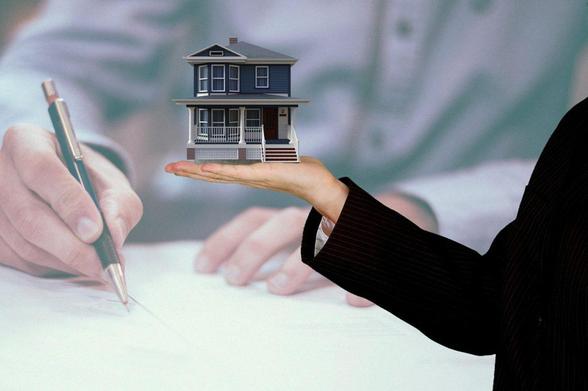 A close-up of a person’s hand holding a detailed house model, illustrating the idea of housing or real estate