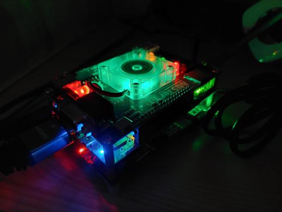 Man sieht das MiSTer FPGA Board in der Dunkelheit. Die Lichter des Lüfters und des Boards selbst leuchten rot, grün und blau.