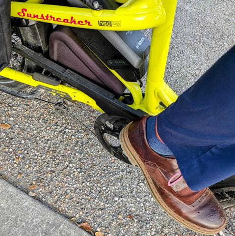 A photo of my right foot on the pedal of a 

yellow Tern HSD cargo bike with its name, Sunstreaker, in red on the seat stay

I'm wearing

brown wingtip spectator derbys with pink laces under a navy pantleg.