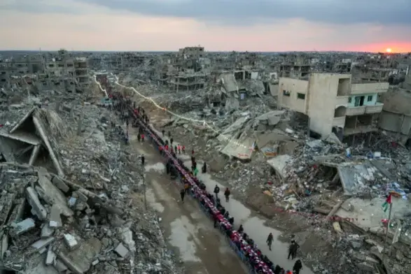 A long row of tables along a cleared path amongst rubble & ruins.