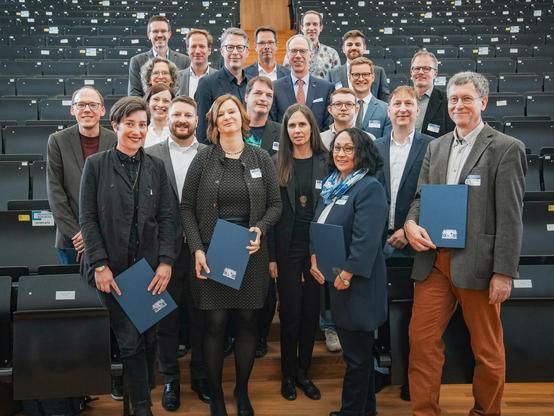 Ein Gruppenfoto verschiedener Personen, die in einem Hörsaal stehen. 