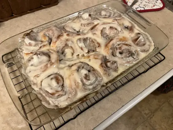 15 delicious looking cinnamon rolls sitting in a glass pan.