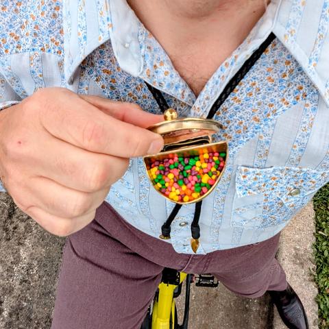 A photo looking down into the bowl of my bolo tie with the lid up, revealing rainbow Nerds candy.