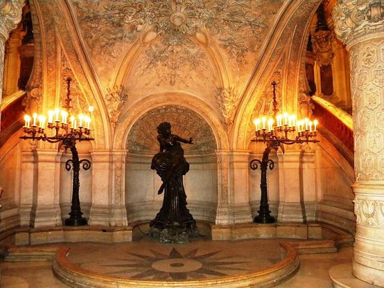 Beleuchtetes Foyer der Opera Garnier in Paris mit der Statue "Pythia" der Bildhauerin Marcello in der Nische.
