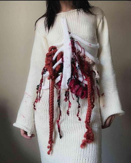 Crocheted sweater with a decorative, visceral design of red and brown threads resembling internal organs and bones.