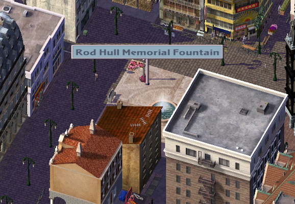 Sim City 4 screen shot, isometric view
A city centre square, wide pedestrian path leads past multi-storey office and retail buildings to a pink-white marbled square, with a sign above it which says

" Rod Hull Memorial Fountain" 

