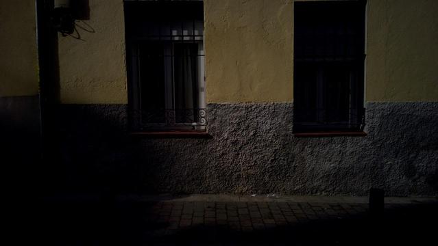 Una pared amarilla y gris con dos ventanas.