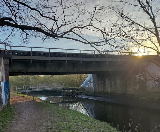 Eisenbahnbrücke und Fußgängerbrücke über den Bach auf meinem Fahrradweg zur Arbeit.