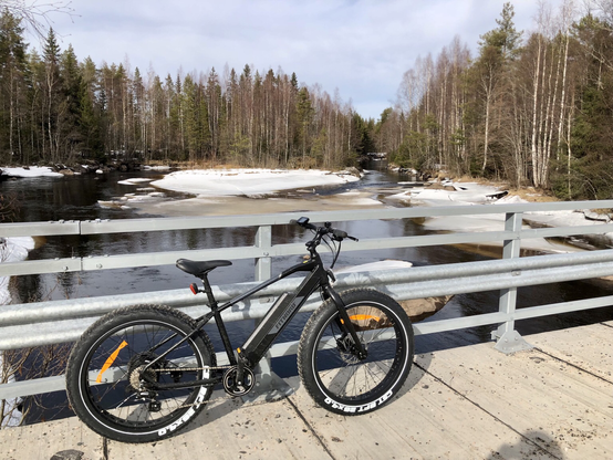 An e-MTB with big tires on a bridge over a river.