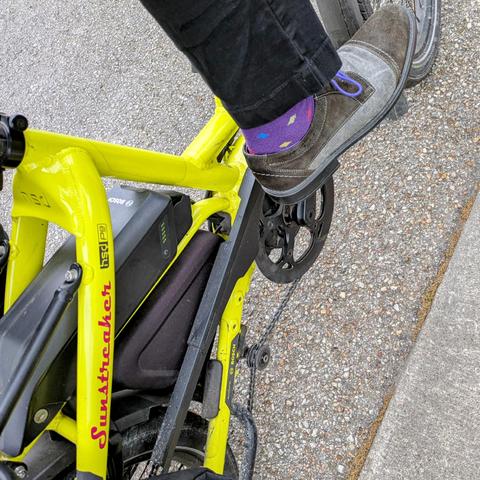 A photo of my right foot on the pedal of a 

yellow Tern HSD cargo bike with its name, Sunstreaker, in red on the seat stay

I'm wearing

Black and grey captoe spectator derbys with purple laces under a black pantleg.