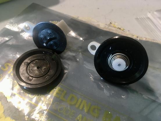 On top of a clear ESD plastic bag sits two Clutch Assembly parts which go in Marantz PMD 720 and PMD 740 multitrack cassette recorders. The assembly on the left is missing its spring and bushing; the one on the right is complete.